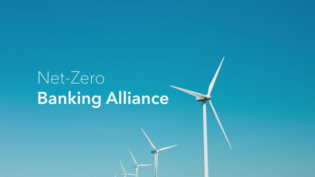 Multiple white wind turbines against a clear blue sky, with the text "Net-Zero Banking Alliance" overlaid.